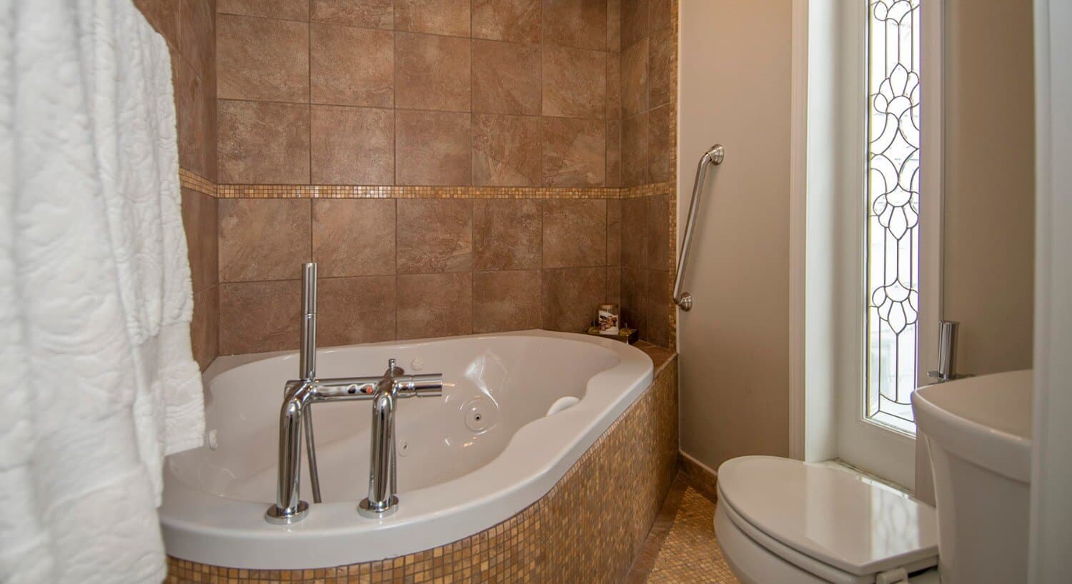 Bathroom tiled in tan with a large soaking tub. 