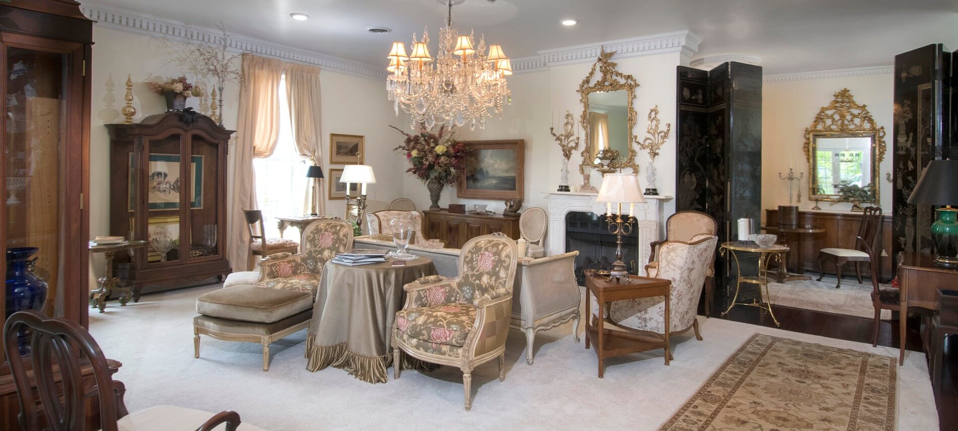 Elegant sitting room in pleasing pastel colors contains antique furniture and a fireplace. 