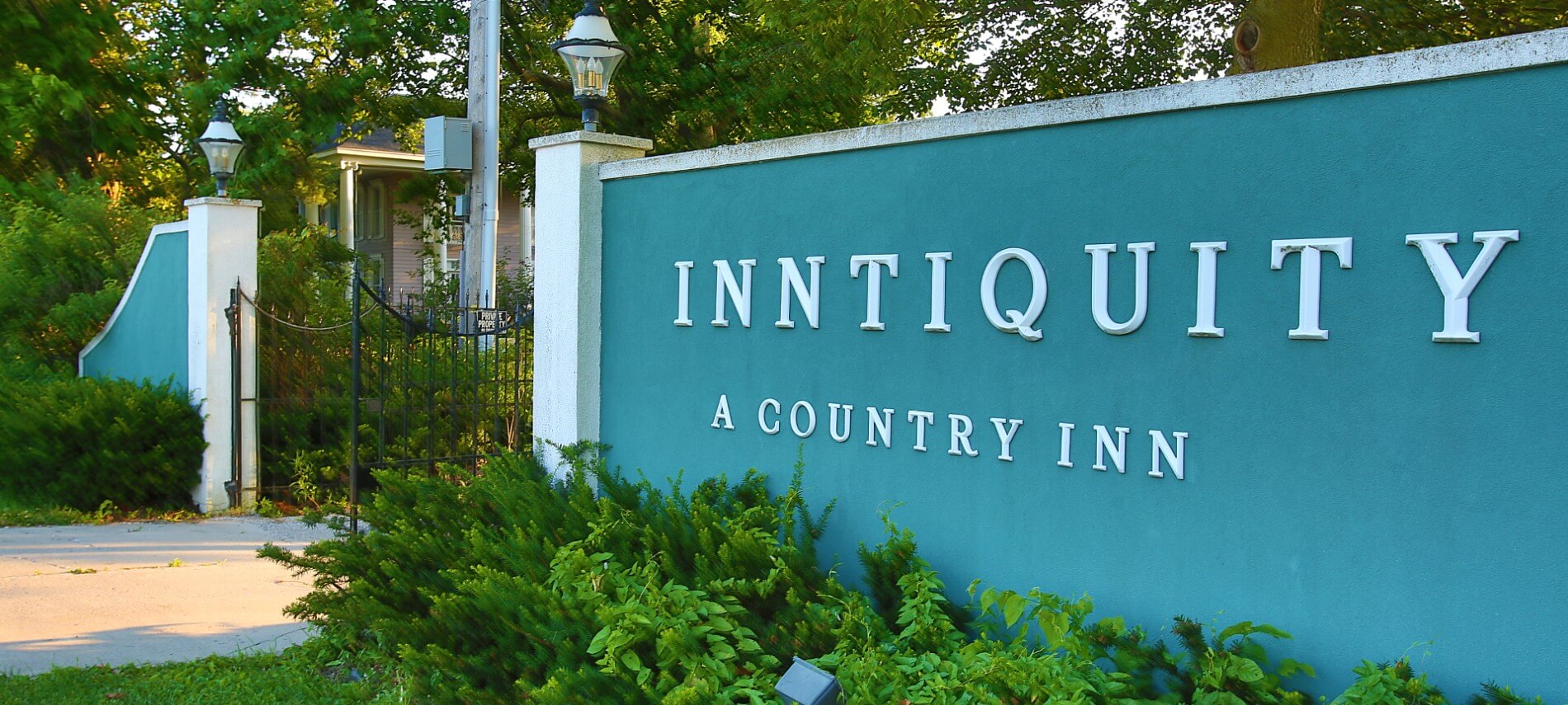 Large stucco and wrought iron fence with the words: Inntiquity, A Country Inn