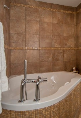 Bathroom tiled in tan with a large soaking tub.