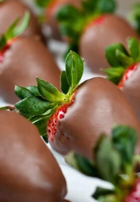 Chocolate covered strawberries on a white surface.